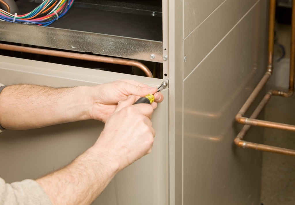 Technician repairing a furnace in West Hills home.