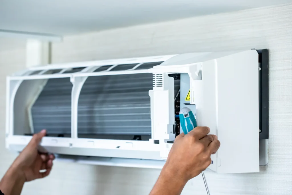 Technician servicing an AC with musty smell in Portland home