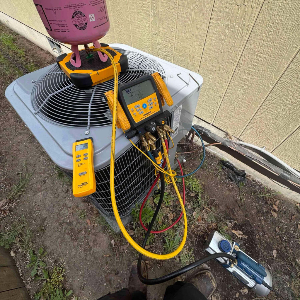HVAC technician servicing an AC condenser unit in Portland with refrigerant gauges and diagnostic equipment