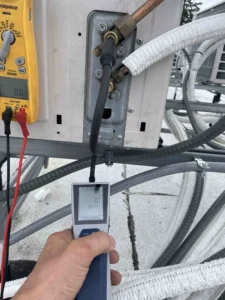Technician performing refrigerant recovery and leak search on a Portland AC system.